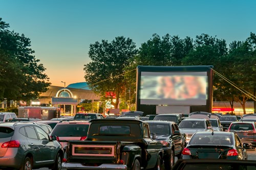 Cars in a parking lot of a drive in cinema at dusk