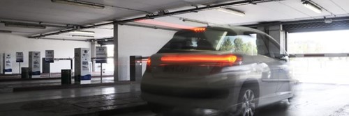 Car with lights on exits parking garage through barrier
