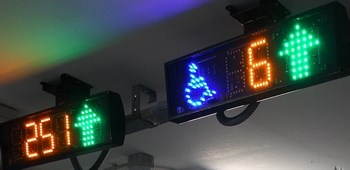 LED displays suspended from ceiling show a blue wheelchair user icon, the number six and a green arrow 