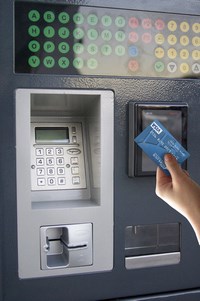 A hand holds a credit card up to an NFC reader on a parking machine