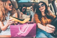 Women in a car take a shoe from a shopping bag