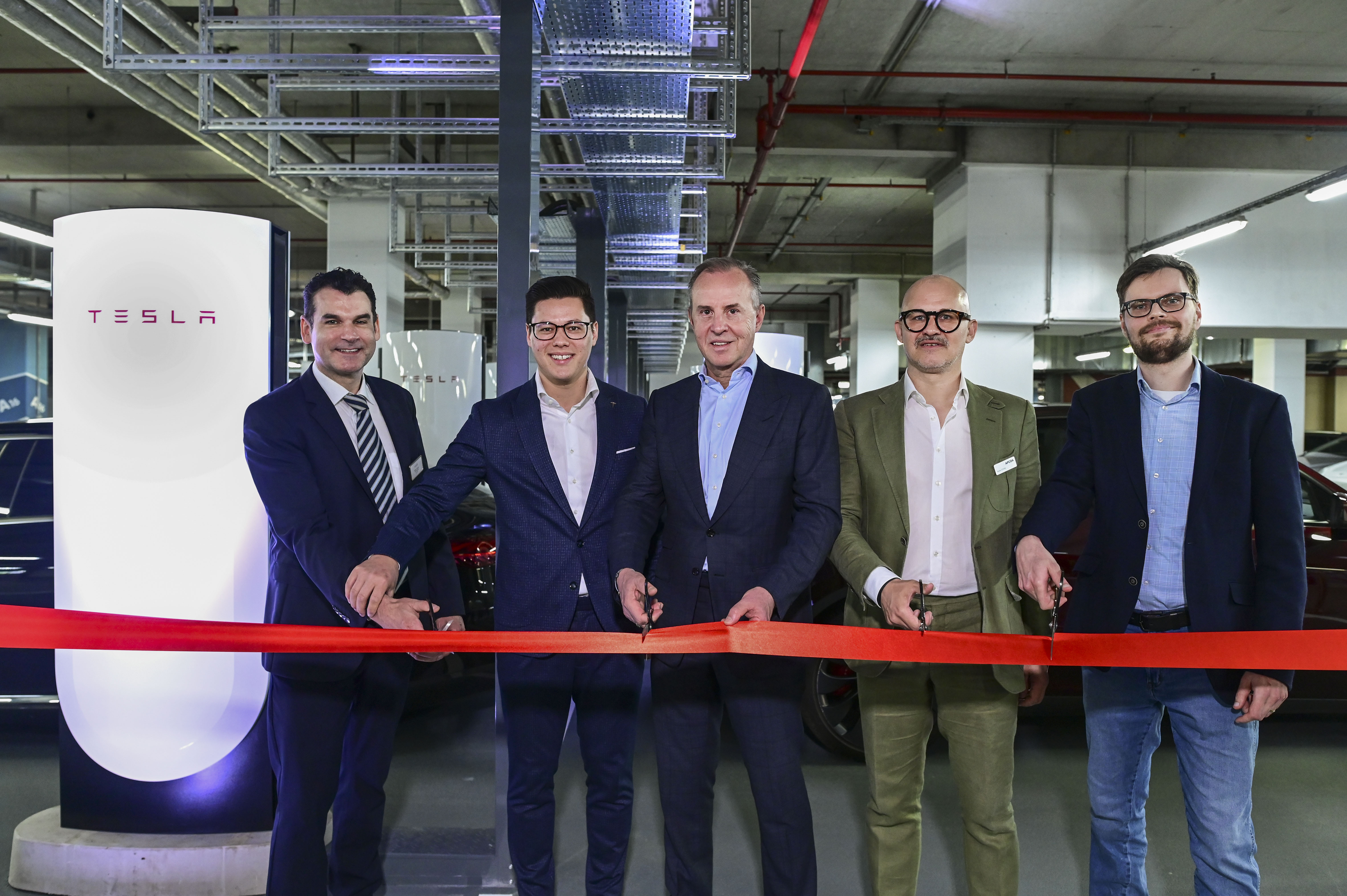 The largest Tesla fast-charging hub in Berlin city centre is being built in the APCOA multi-storey car park at the ALEXA shopping centre:  (from left to right) Oliver Hanna, Centre Manager ALEXA Shoppingcenter Berlin / Sierra Germany, Malte Kendel, Authorised Representative & Manager Charging / Tesla, Philippe Op de Beeck, Chief Executive Officer / APCOA, Niels Christ, Group Director Urban Hubs / APCOA and Martin Sölle, Senior Project Manager Innovation / Berlin Agency for Electromobility eMO