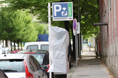 Cars parked along the curb with a parking meter covered in a white plastic bag.