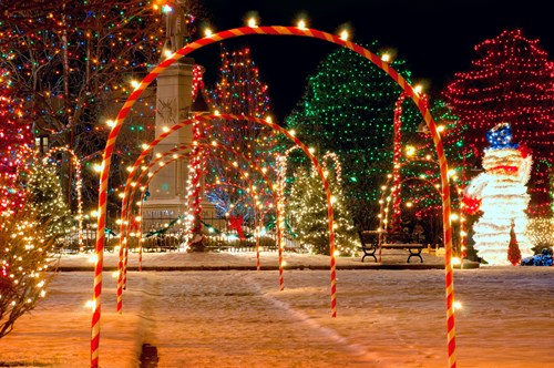 Christmas lights with candycane arches and a snowman, on a snowing village square