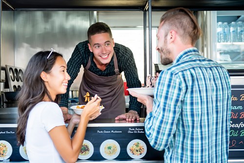 Man and woman buy food from a food truck.