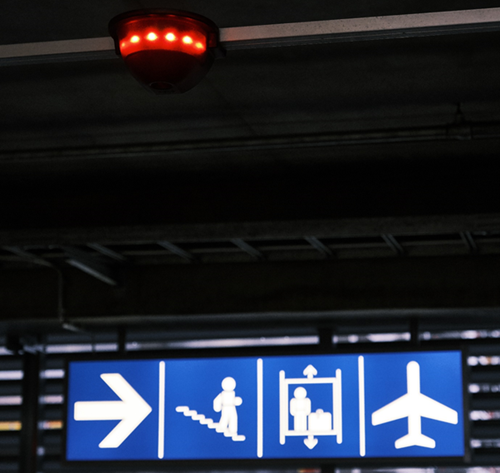 A parking guidance sensor displays a red light and a blue sign shows an arrow, stairs, lift and aeroplane