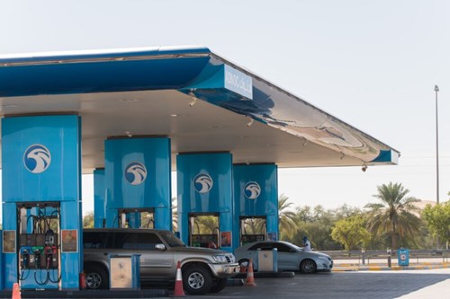 Blue petrol station with two silver cars using the pumps.
