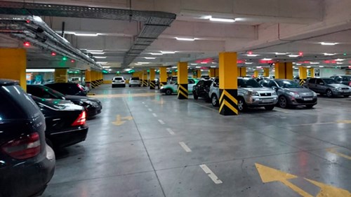Inside a parking garage, bays are marked by yellow lines and parking guidance lights shine red or green