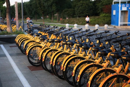 Yellow hire bikes docked on a sidewalk